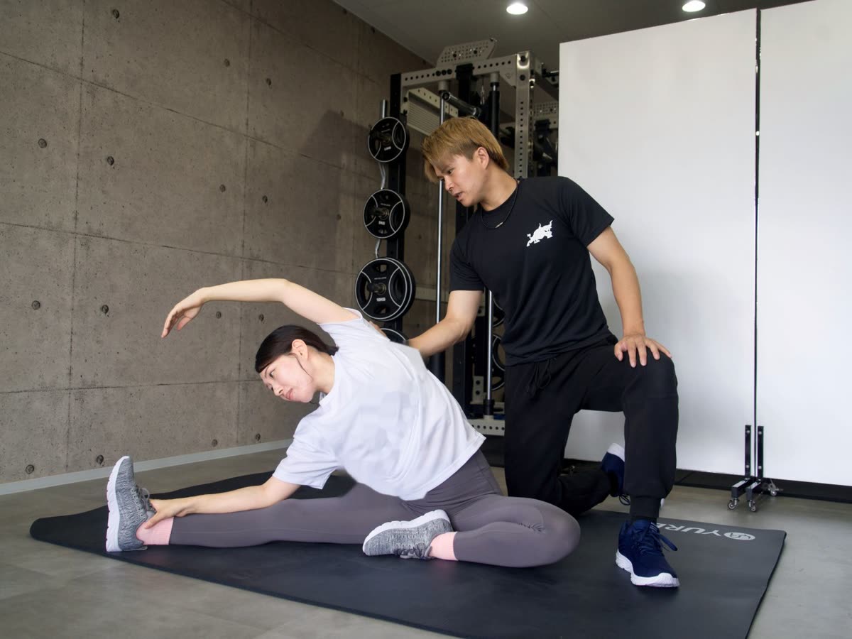トレーナーがお客様のストレッチをそばで見ながら指導している様子
